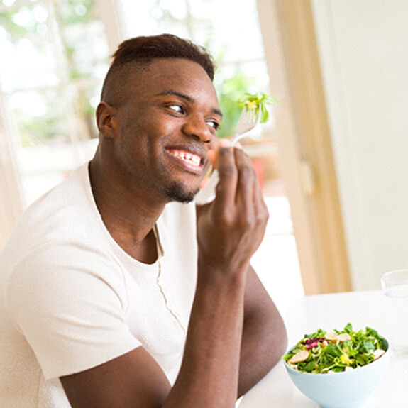 a person eating a salad at a table with a glass of water