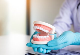 Gloved hands carefully holding model dentures