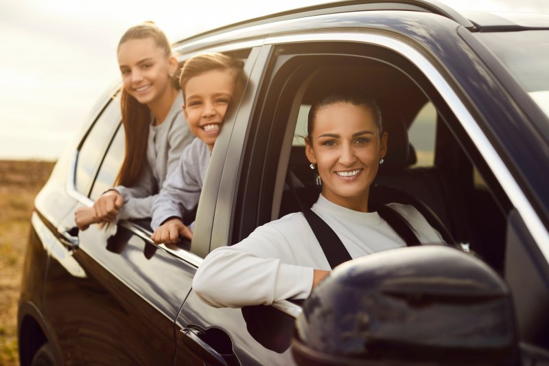 A smiling mother and her kids traveling in a car