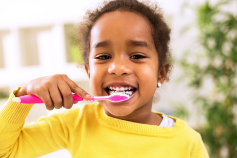 child smiling while brushing teeth 